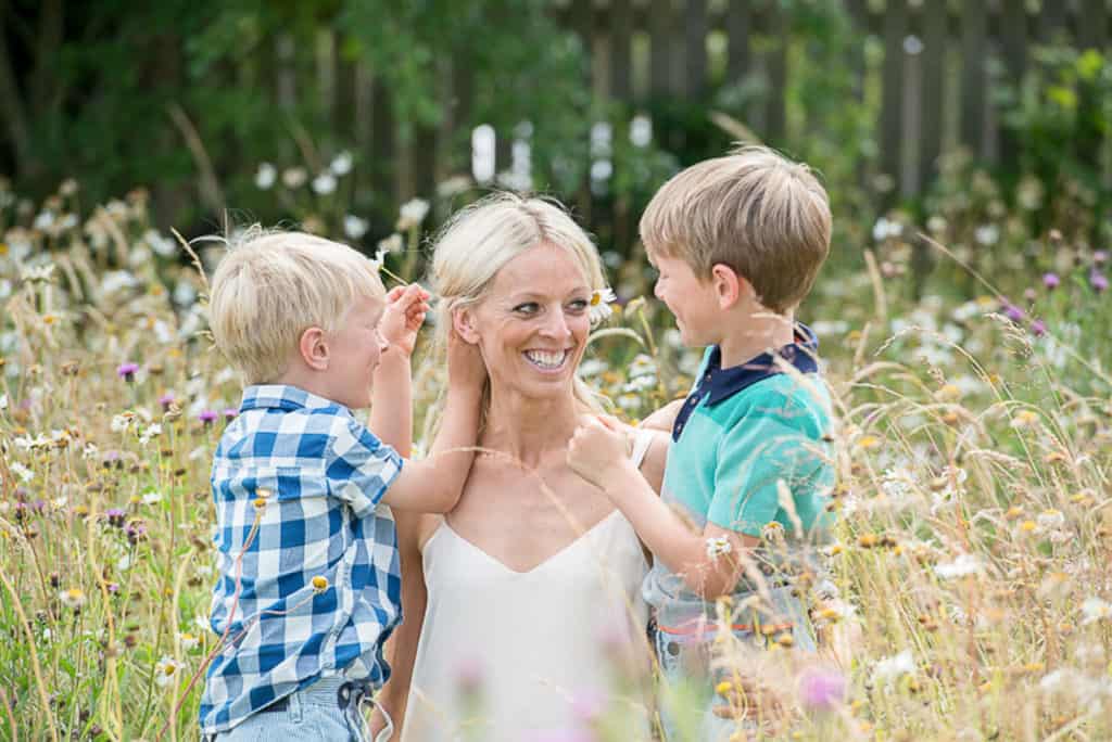 Family photoshoot, mum with two boys sitting in grass meadow